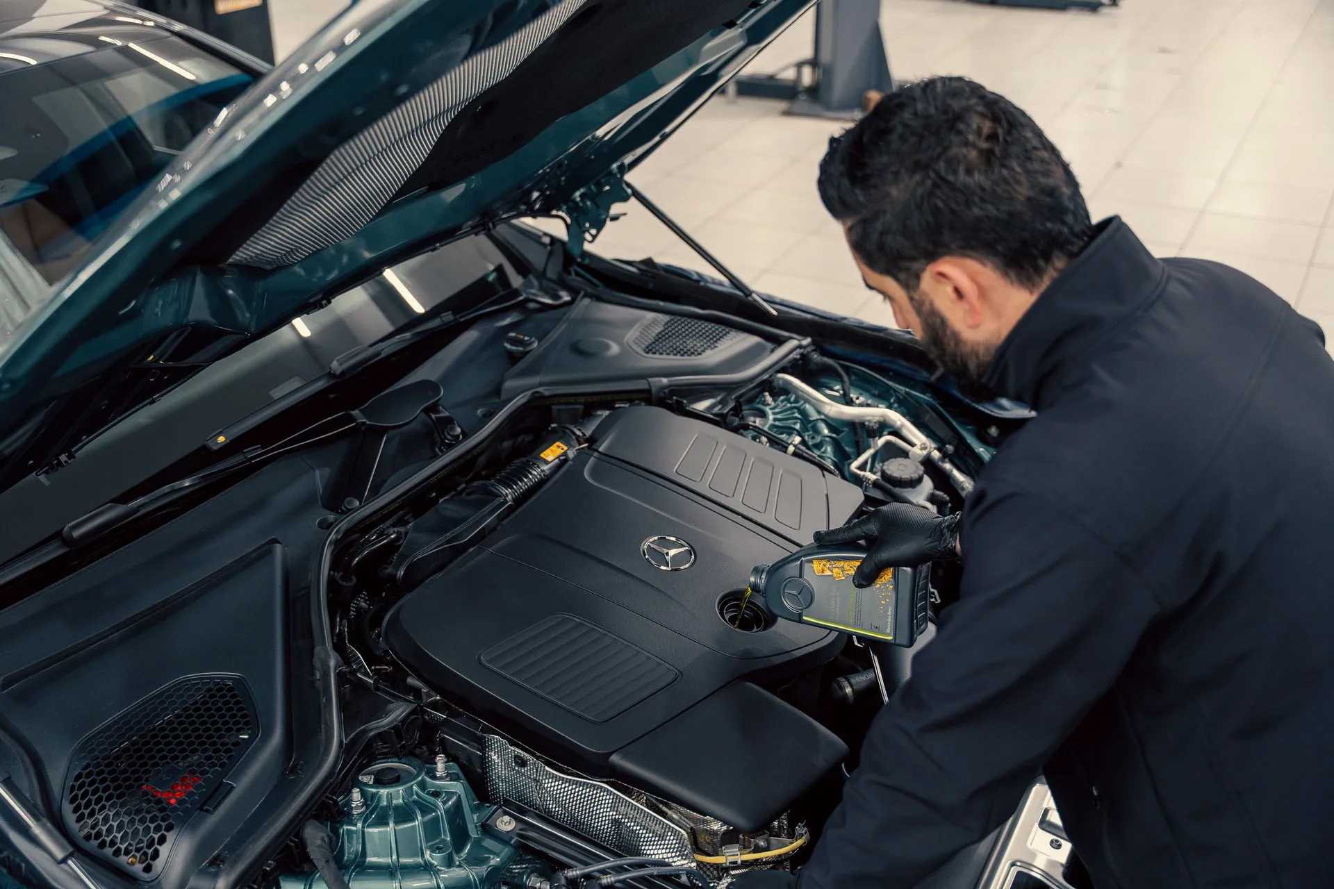 A technician checking a reconditioned car's engine bay